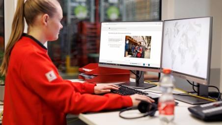Logistikmitarbeiterin von Kaufland bei der Arbeit am Schreibtisch mit zwei Bildschirmen.